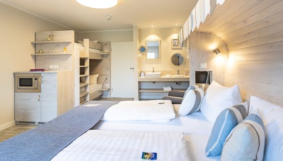 Im Vordergrund ist das Doppelbett im Strandkorb-Stil zu sehen, im Hintergrund das Etagenbett und die Waschecke